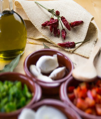  Fresh ingredients for cold tomato soup, tomatoes, peppers, onion, garlic, olive oil. On a wooden table and clay utensils