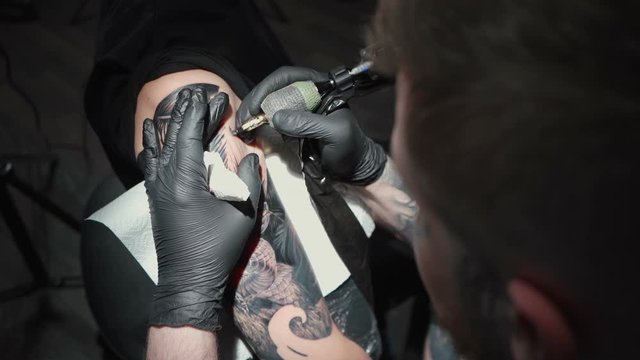 Video of man doing tattoo of snake in studio
