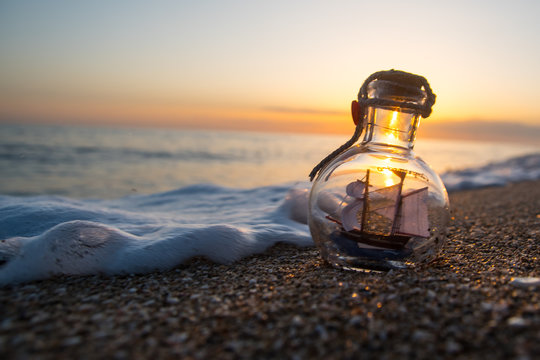 small sailing ship in a bottle at sea with beautiful sunset