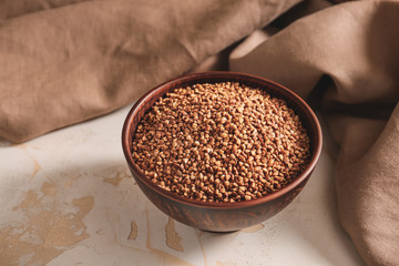 Bowl with raw buckwheat on table