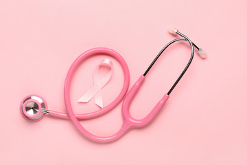 Fototapeta premium Pink ribbon with stethoscope on color background. Breast cancer awareness concept