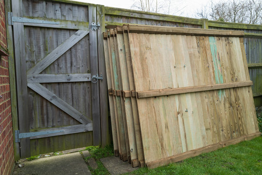 Replacement fence panels with vertical slats stacked waiting for installation in a residential back garden or yard..