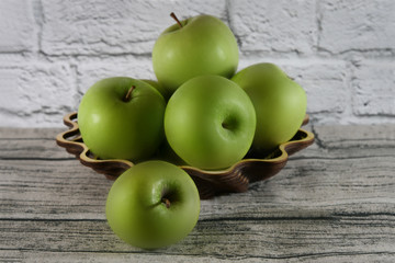 Green apples in a wooden basket on a wooden table