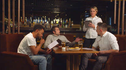 Waiter takes order on tablet from company of friends