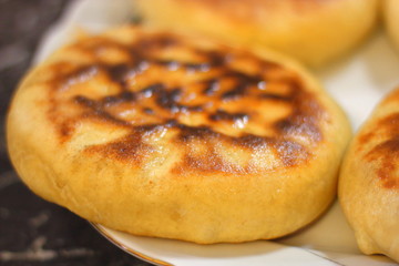 Fried round pies on a white dish on a black background.