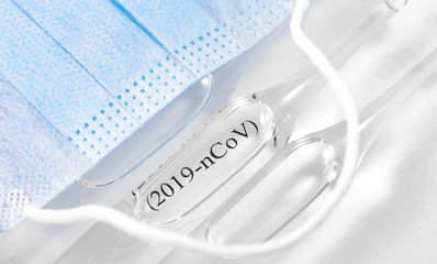 Novel coronavirus (2019-nCoV). Respirator mask and flasks with text (2019-nCoV) on white background closeup