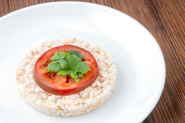 Rice cakes with tomato on a white plate on a wooden table