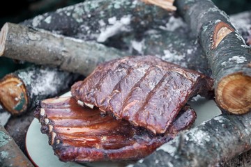 Sliced fresh hot pork ribs lie outside on a plate at a picnic