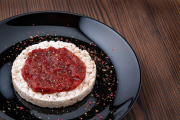 Rice cakes with spicy red sauce on a black plate on a wooden table