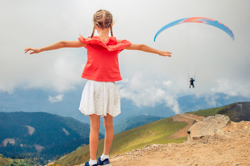 Beautiful happy little girl in mountains in the background of fog