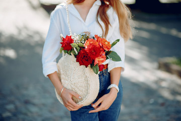 Beautiful girl in a white blouse. Woman in a summer city. Lady with bouquet of flowers