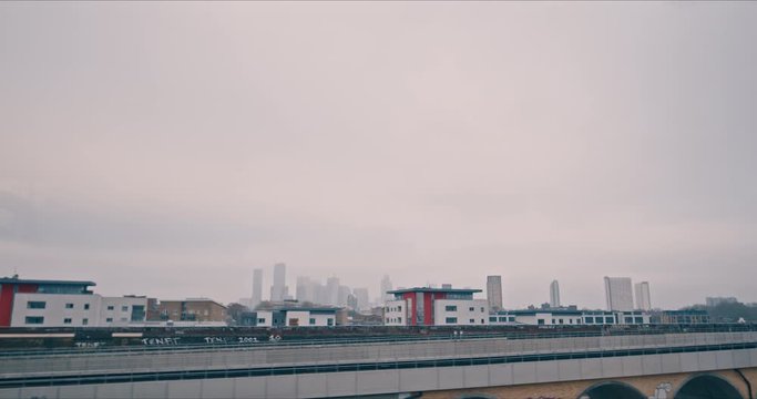 Commuter Train Passing Railway London City Skyline Flat Block Cloudy Transport	
