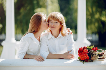 Naklejka premium Elegant mother with young daughter. Family in a park. Women with a bouquet of flowers