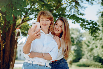 Fototapeta premium Elegant mother with young daughter. Family in a park. Women in a white shirts