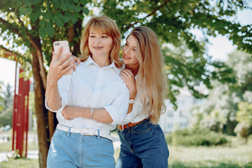 Elegant mother with young daughter. Family in a park. Women in a white shirts