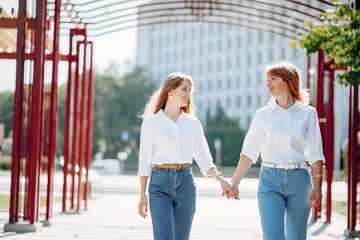 Elegant mother with young daughter. Family in a park. Women in a white shirts