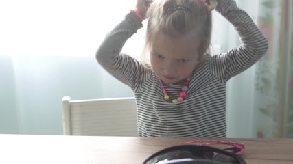 The little girl wears elegant jewelry and funny glasses in the form of hearts. A child dress up at home