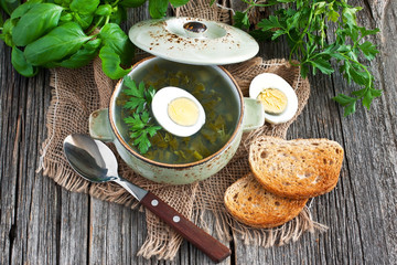 Fresh vegetable soup made of  potato and sorrel  in bow  lon old wooden table 