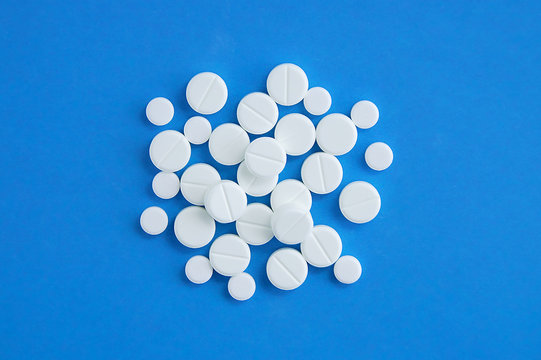 White round pills on a blue background. Medical preparations.