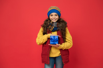 winter girl with new year present box. happy winter holidays. small girl knitted hat and scarf. ready for christmas. she is going on xmas party. seasonal shopping sales. childhood happiness