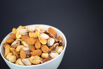 Hazelnut ,Pecan nut, Pistachio nut ,Peanuts nut,Almond nut mixed salt in a wooden plate is Protein food and healthy food for diet food on a black background.