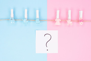 Gender reveal party invitation concept. Background photography of small pegs with carriage toys isolated on divided into two parts background question mark in center