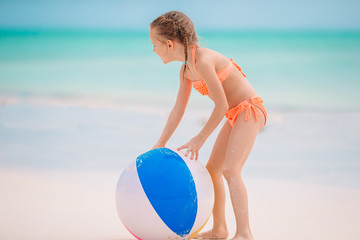 Naklejka na ściany i meble Little adorable girl playing on beach with ball