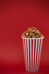 Butter popcorn in a red popcorn cup, snack in the house or cinema on a red background