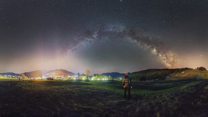 Person looks at the night sky with a milky way near the city