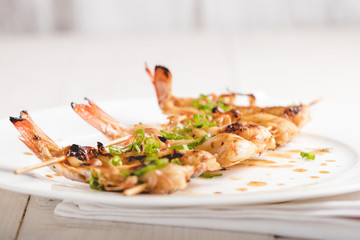 Grilled shrimp skewers. Seafood, shelfish. Shrimps Prawns skewers with spices and fresh herbs on white wooden background