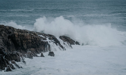 The waves of the ocean hit the rocks with small splashes