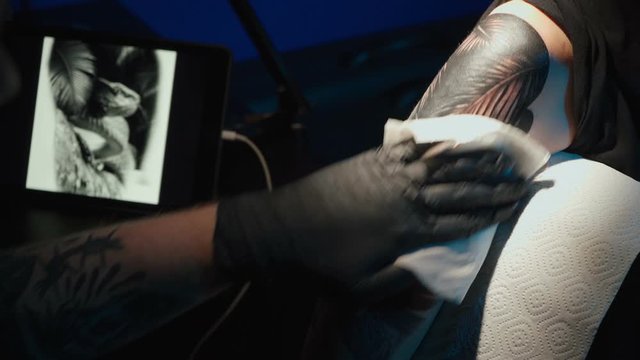 Close up video of man doing tattoo of snake for woman in studio