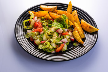 fresh vegetable salad and perfectly fireproof potato on a black plate, white background