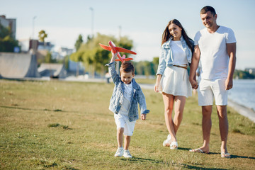 Family in a summer park. Father in a white shirt. Cute little son with airplane