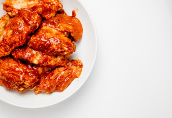 Marinated chicken wings in a plate on a white background
