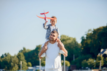 Family in a summer park. Father in a white shirt. Cute little son with an airplane