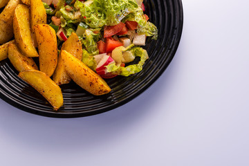fresh vegetable salad and perfectly fireproof potato on a black plate, white background