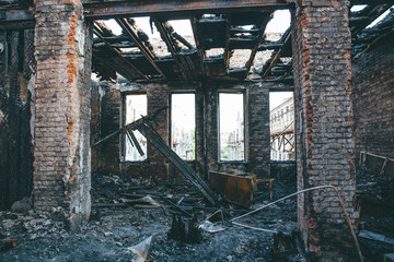 Burnt house interior inside, burned ruined room, remains of furniture in black soot on floor. Fire or war consequences concept.