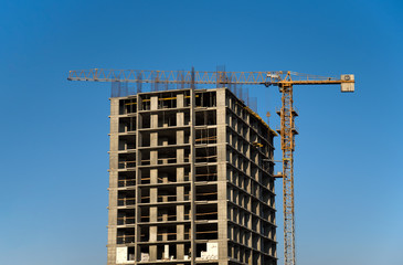 Fototapeta na wymiar Tower cranes constructing a new residential building at a construction site against blue sky. Renovation program, development, concept of the buildings industry.