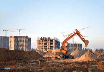 Bucked wheel excavator digs ground at a construction site for installing concrete storm pipes....