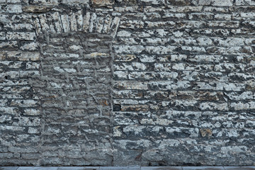 The doorway in the old wall is laid with stone blocks. Gray stones are covered with long-term plaque of dark color. Background. Texture.