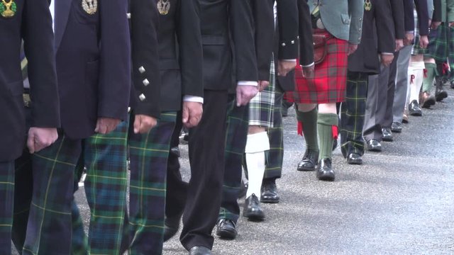 People in Kilts Marching during Parade in Scotland. Many are wearing Scottish Tartan