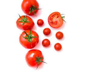 Delicious ripe red tomato lies on white background next to few cherry tomatoes. Top view. Healthy and organic food concept. 