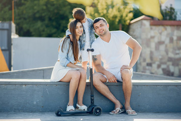 Obraz premium Family in a summer park. Father in a white shirt. Cute little son with a scooter