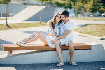 Couple in a park. Blonde in a blue shirt. Man in a white t- shirt