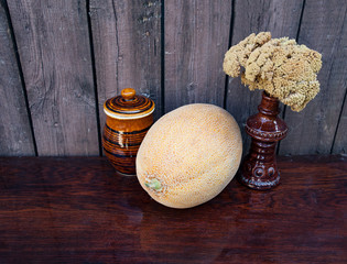 Still life of melon, dried flowers and clay pots with honey