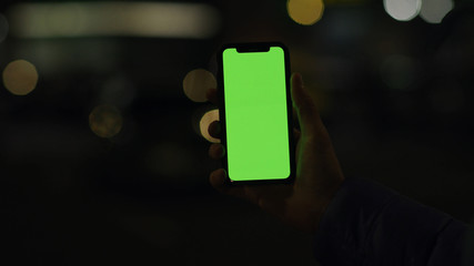 Lviv, Ukraine - May 19, 2018: On dark man hands holding use touch phone with vertical green screen street background sunset busy finger touch message cellphone display girl slow motion