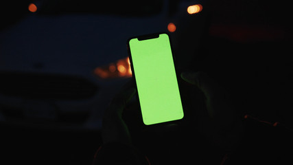 Lviv, Ukraine - May 19, 2018: On dark man hands holding use touch phone with vertical green screen street background sunset busy finger touch message cellphone display girl slow motion © america_stock