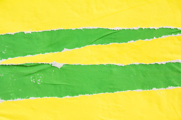 Green and yellow ripped crumpled and peeling paper posters on urban billboard texture background. Copy space for text message.