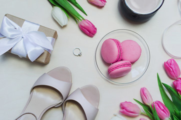 Coffee cup, spring tulip flowers and pink macarons on pastel table top view vertical. Greeting for Womans or Mothers Day